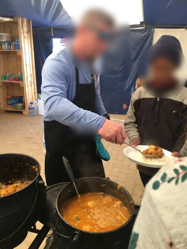 A volunteer dishing up a hot meal